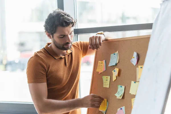 Businessman working with sticky notes on board in office — Stock Photo