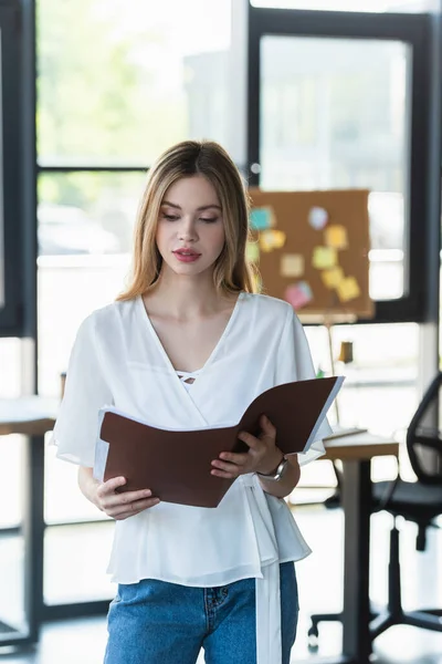 Jeune femme d'affaires tenant dossier papier dans le bureau — Photo de stock