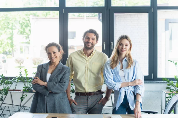 Усміхнені міжрасові ділові люди дивляться на камеру в офісі — Stock Photo