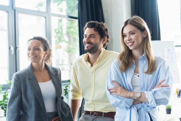 Positive multiethnische Geschäftsleute, die im Amt wegschauen — Stockfoto