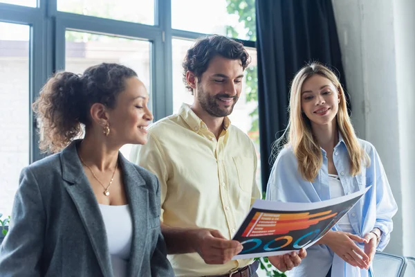 Cheerful interracial businesspeople working with document in office — Stock Photo