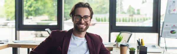 Empresário sorridente em óculos olhando para a câmera no escritório, banner — Fotografia de Stock