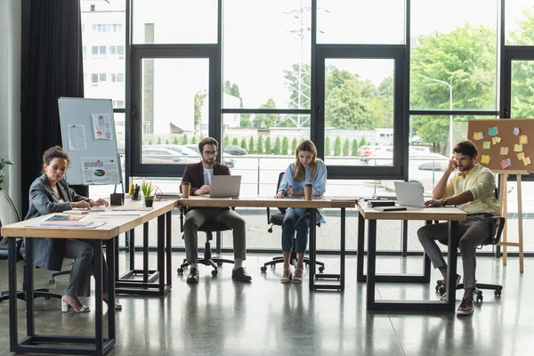 Interrassische Geschäftsleute nutzen Laptops und arbeiten im Büro mit Papieren — Stockfoto