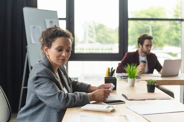 African american businesswoman looking at calculator near smartphone and documents in office — Stock Photo