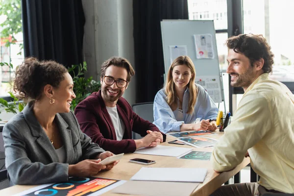 Gente de negocios sonriendo a un colega afroamericano con calculadora en la oficina — Stock Photo