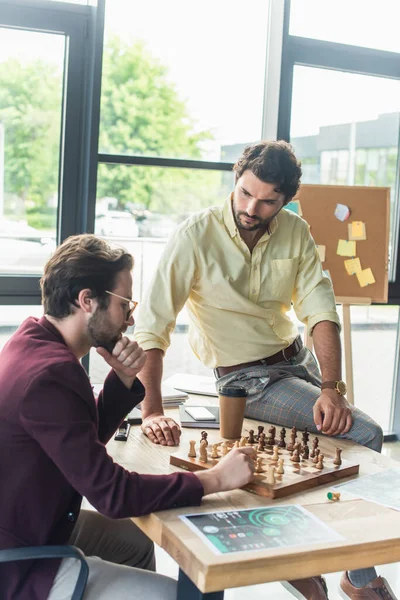 Business people in formal wear playing chess near papers in office — Stock Photo