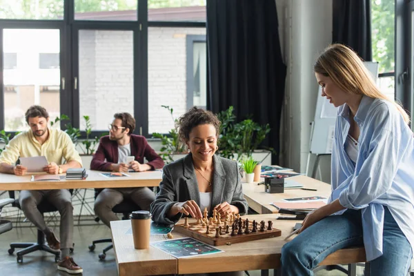 Позитивна афроамериканська бізнесменка, яка грає в шахи зі своїм колегою на посаді. — стокове фото