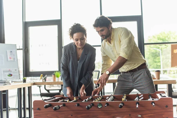 Businessman pointing at table football near african american colleague in office — Stock Photo