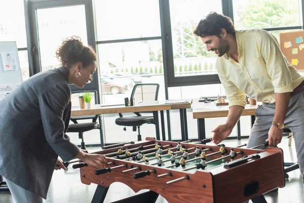 Seitenansicht von interrassischen Geschäftsleuten, die im Büro Tischfußball spielen — Stockfoto