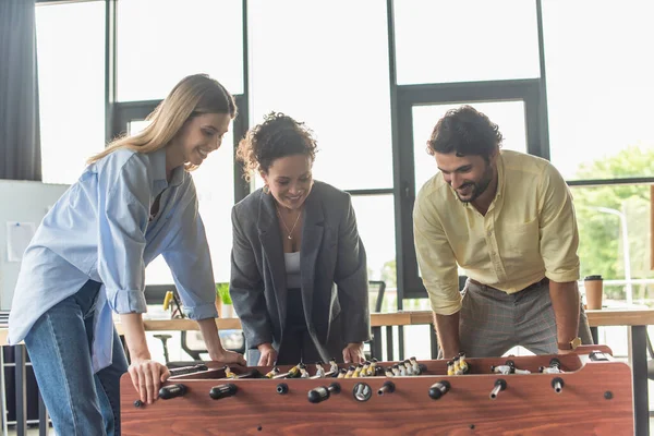 Des hommes d'affaires multiethniques joyeux jouant au baby-foot au bureau — Photo de stock