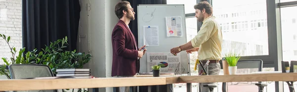 Side view of businessmen working together near flipchart in office, banner — Stock Photo