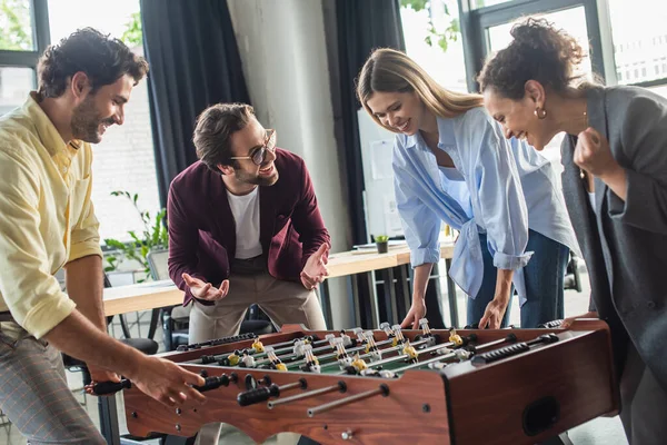 Empresários inter-raciais excitados jogando futebol de mesa no escritório — Fotografia de Stock