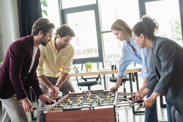 Gente de negocios multicultural jugando fútbol de mesa juntos en la oficina - foto de stock