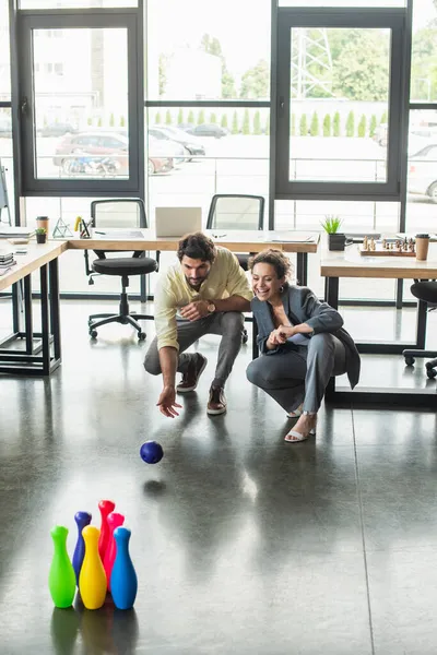 Gente de negocios interracial feliz jugando bolos en la oficina - foto de stock