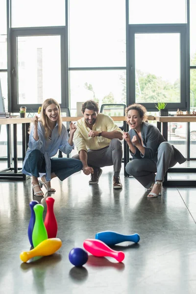 Des hommes d'affaires multiethniques positifs jouant au bowling au bureau — Photo de stock