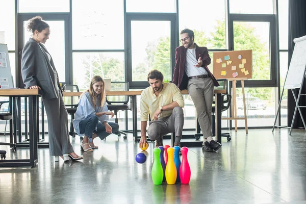 Negocio interracial positivo gente jugando bolos en la oficina - foto de stock