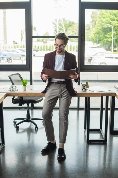 Geschäftsmann in offizieller Kleidung blickt im Büro auf Papiermappe — Stockfoto