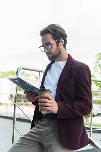 Empresário em desgaste formal e óculos segurando café para ir e papel ao ar livre — Fotografia de Stock