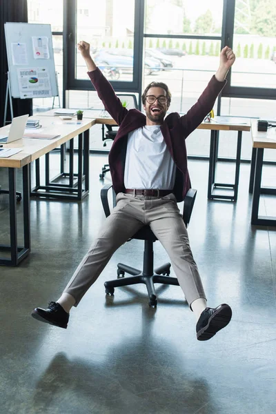 Excited businessman showing yes gesture on chair in office — Stock Photo