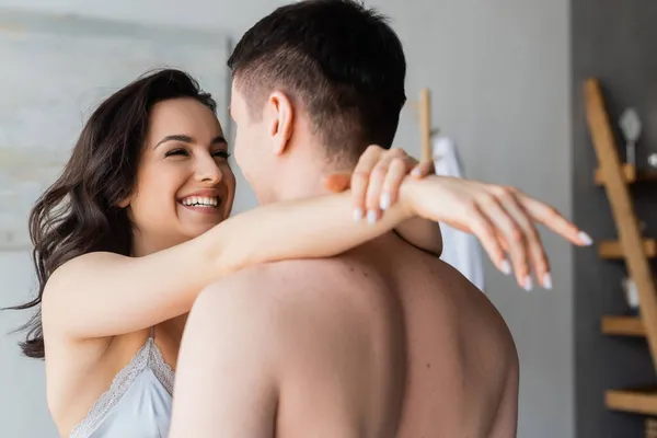 Mujer feliz en sujetador abrazando novio sin camisa en el dormitorio - foto de stock