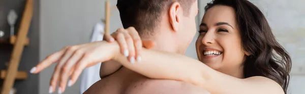 Feliz mujer abrazando sin camisa novio, bandera - foto de stock