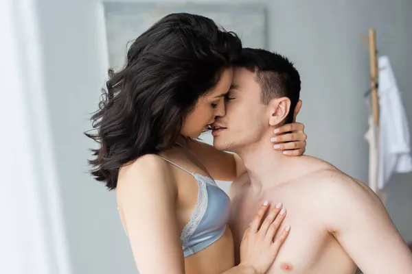 Sexy young woman in bra kissing shirtless boyfriend — Stock Photo