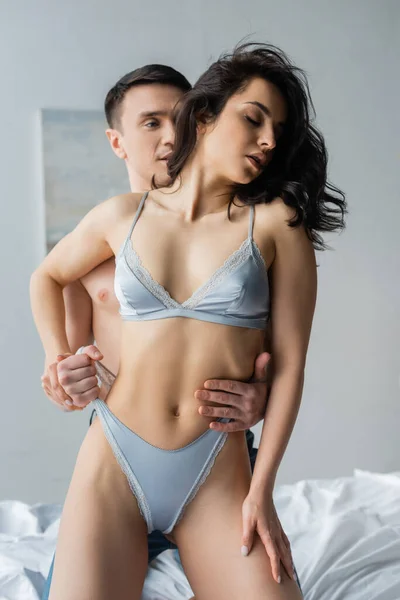 Man touching panties of sexy girlfriend in bedroom — Stock Photo