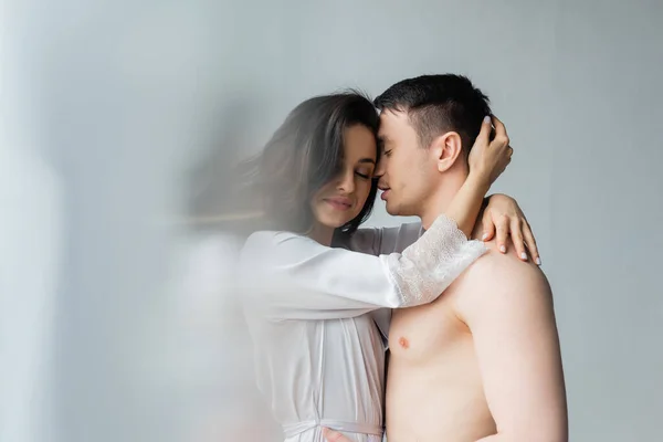Feliz joven pareja abrazándose en el dormitorio - foto de stock