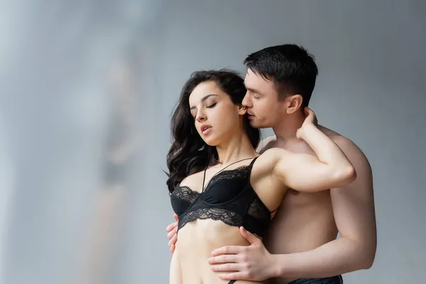Shirtless man seducing brunette woman in black lace bra — Stock Photo