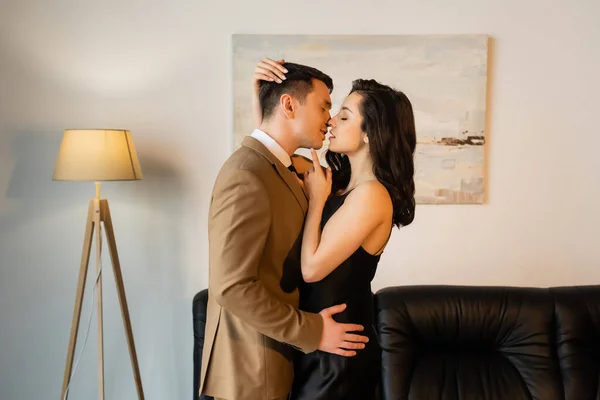 Side view of seductive woman in slip dress kissing man in suit — Stock Photo