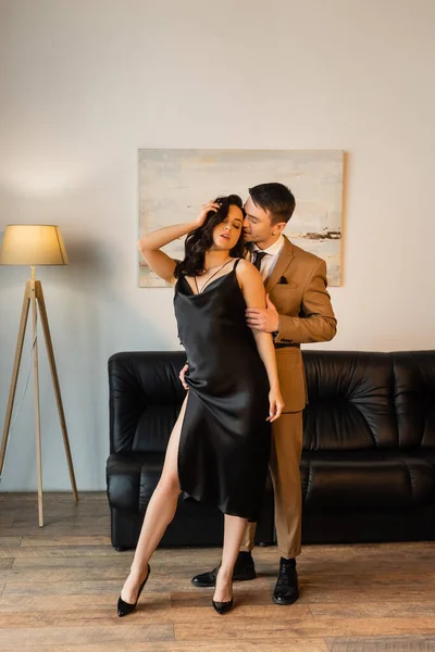 Full length of man in suit seducing brunette woman in slip dress — Stock Photo