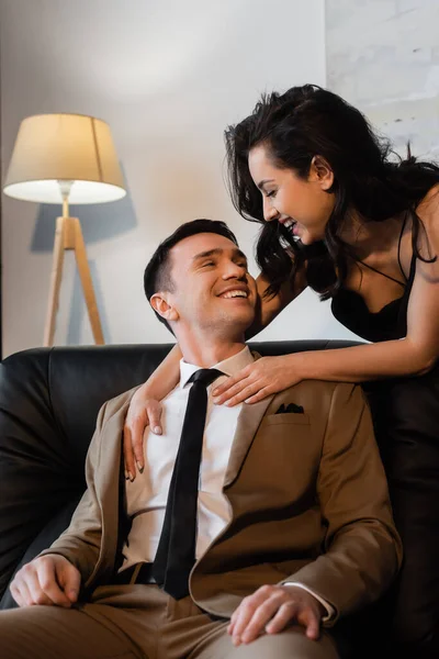 Happy brunette woman hugging smiling man on couch — Stock Photo