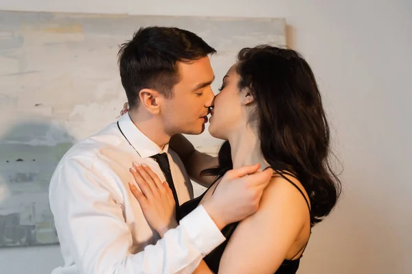 Joven y apasionada pareja besándose en casa - foto de stock