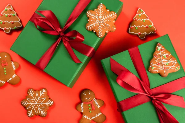 Top view of green wrapped presents near gingerbread cookies on red background — Stock Photo