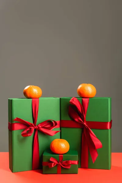 Mandarines sur des cadeaux enveloppés verts isolés sur gris — Photo de stock