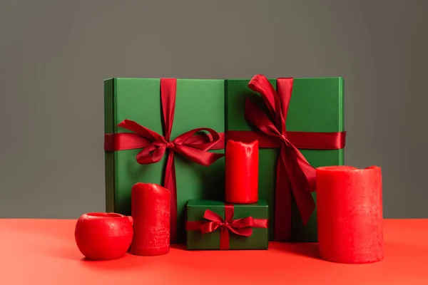 Red candles near green wrapped presents isolated on grey — Stock Photo