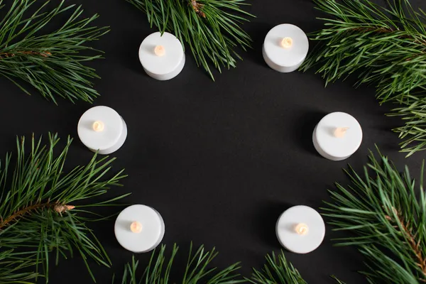 Top view of candles and pine branches on black — Stock Photo