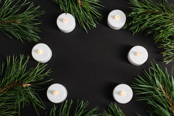 Top view of candles and pine branches on black — Stock Photo