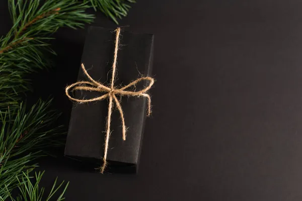 Top view of gift box near fir branches on black — Stock Photo