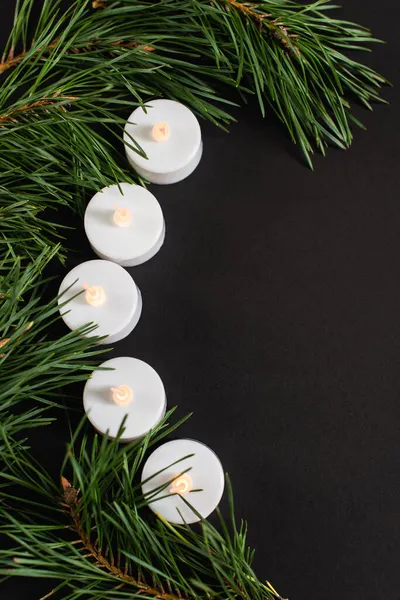 Vue de dessus des bougies près des branches de sapin isolées sur noir — Photo de stock