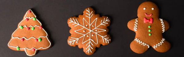 Top view of different shapes gingerbread cookies on black, banner — Stock Photo