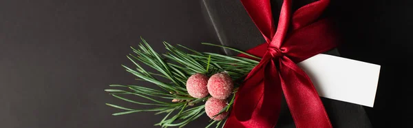 Top view of wrapped gift box with red ribbon and blank card isolated on black, banner — Stock Photo