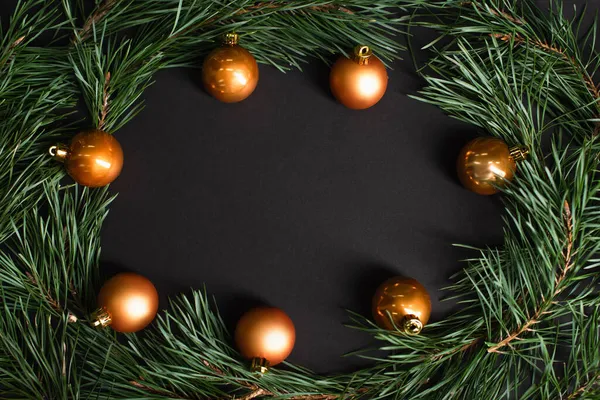 Flat lay with golden christmas balls near fir branches on black — Stock Photo