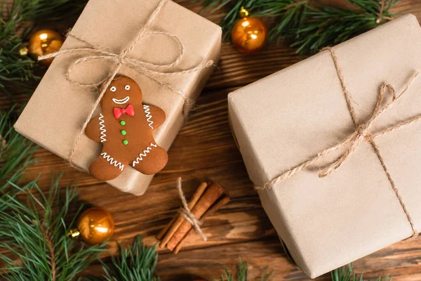 Top view of gingerbread cookie on gift box near blurred pine branches and cinnamon sticks on wooden surface — Stock Photo
