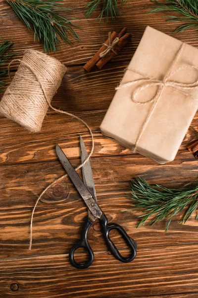 Vista superior de la caja de regalo envuelta cerca de tijeras en la superficie de madera - foto de stock