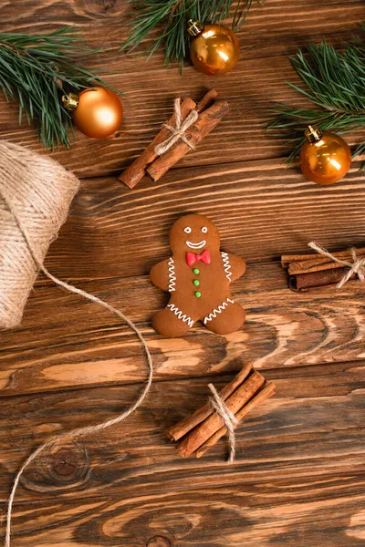 Vue de dessus du biscuit au pain d'épice, bâtonnets de cannelle et branches de sapin sur la surface en bois — Photo de stock