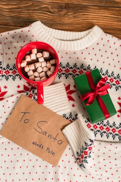 Top view of letter to santa near gift box and cocoa with marshmallows on knitted sweater — Stock Photo