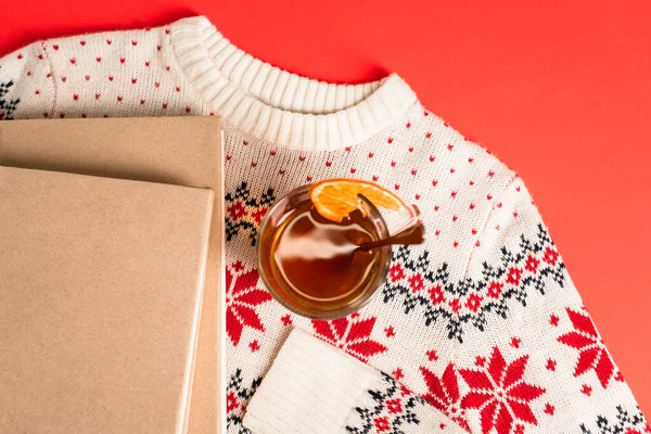 Vista dall'alto di libri e tazza di tè su maglione lavorato a maglia su rosso — Foto stock