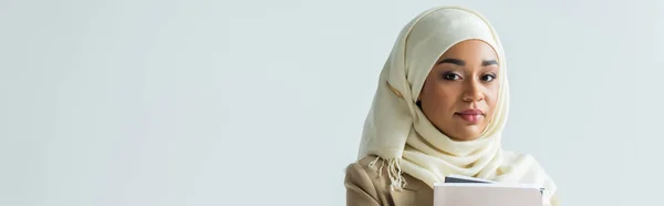 Mujer de negocios en hijab sosteniendo carpetas aisladas en gris, bandera - foto de stock