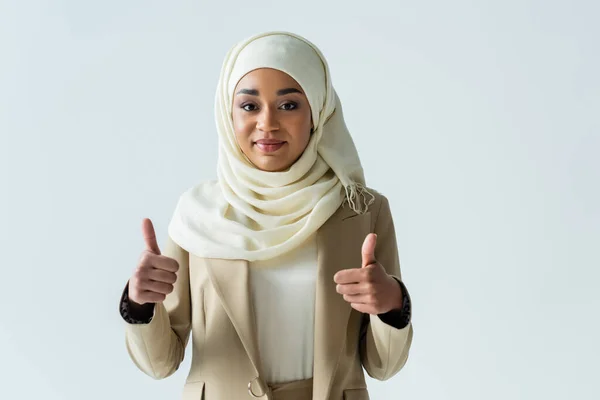 Happy muslim woman in hijab showing thumbs up and smiling isolated on grey — Stock Photo